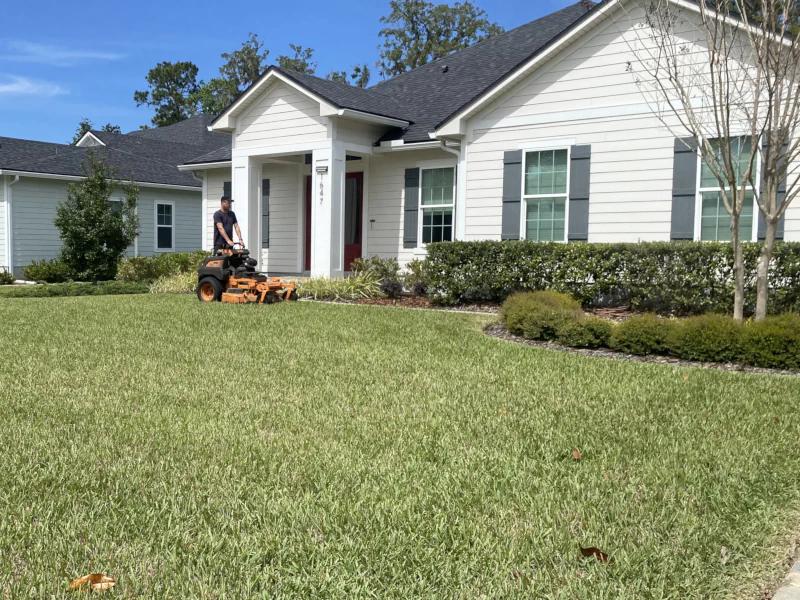 mowing very attractive lawn in Fleming Island, FL with lots of trimmed hedges