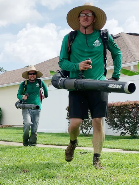 brothers with backpack blowers walking on lawn in Middleburg, FL.